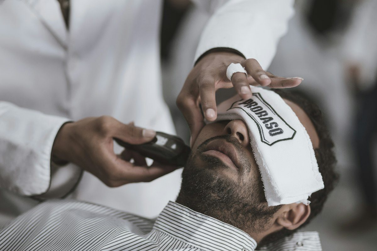 Man shaving lying man