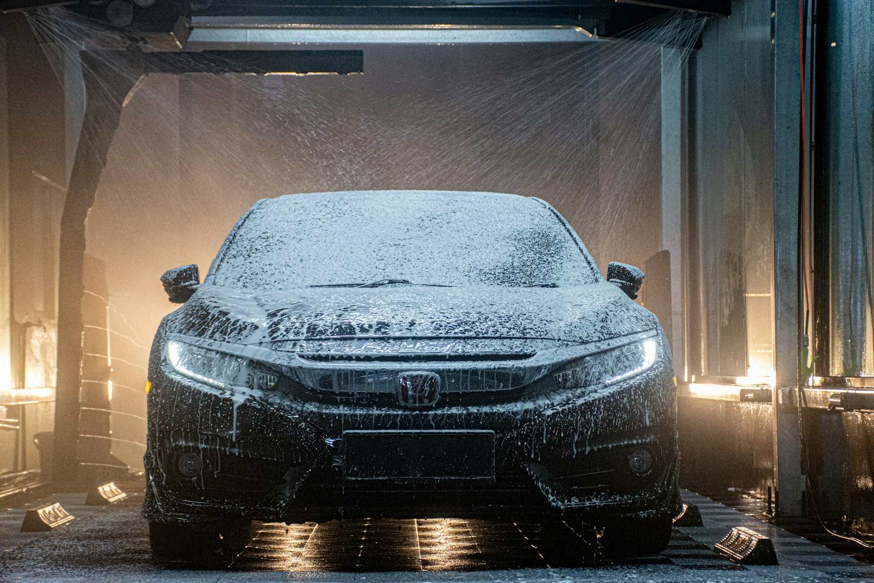 A car is covered in snow in a garage