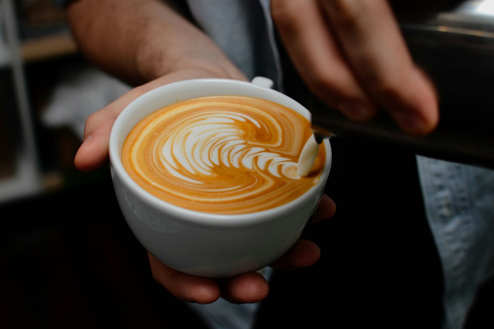Latte with rosetta art held in two hands