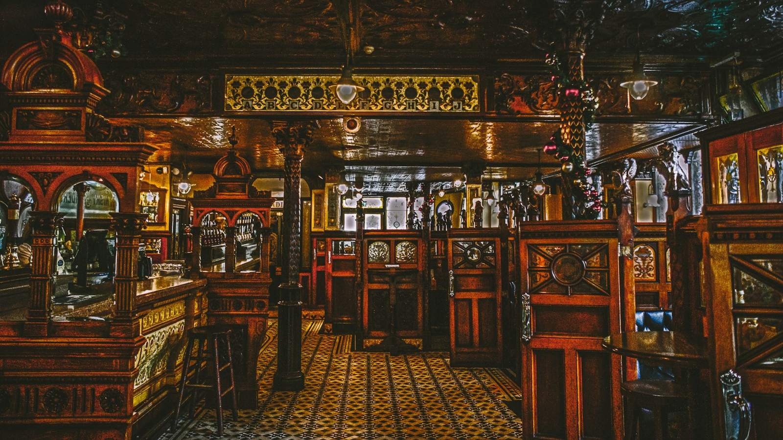 The carved wooden bar and tiled floor of the pub at night
