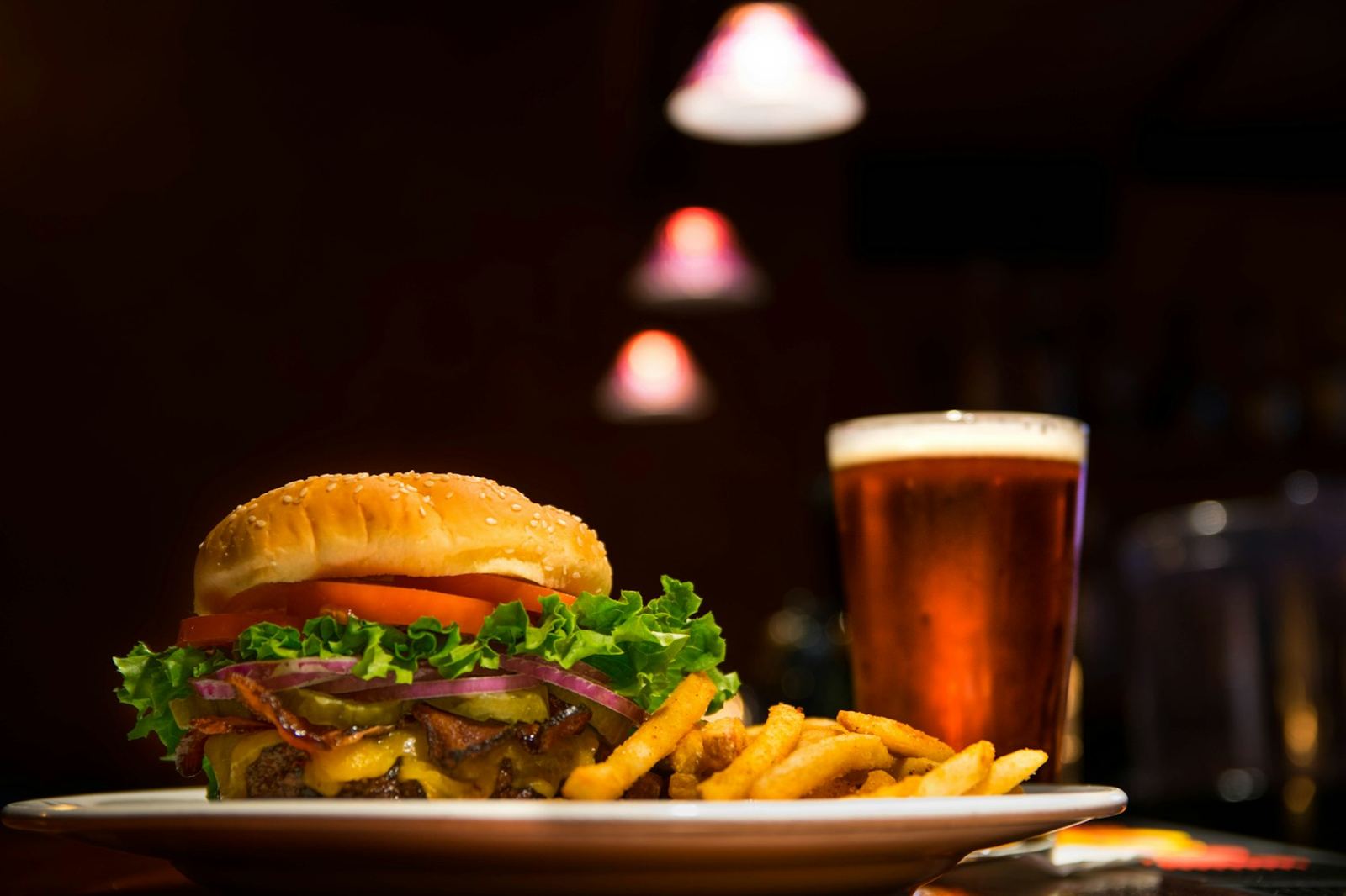 A tall pub burger with fries and a pint of ale