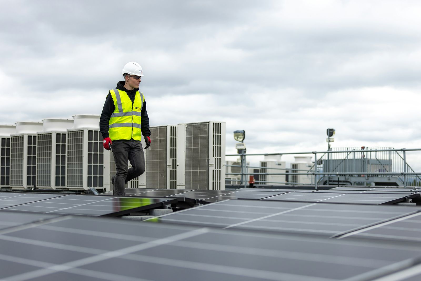 Corbel technician walking past rooftop HVAC units on a commercial building