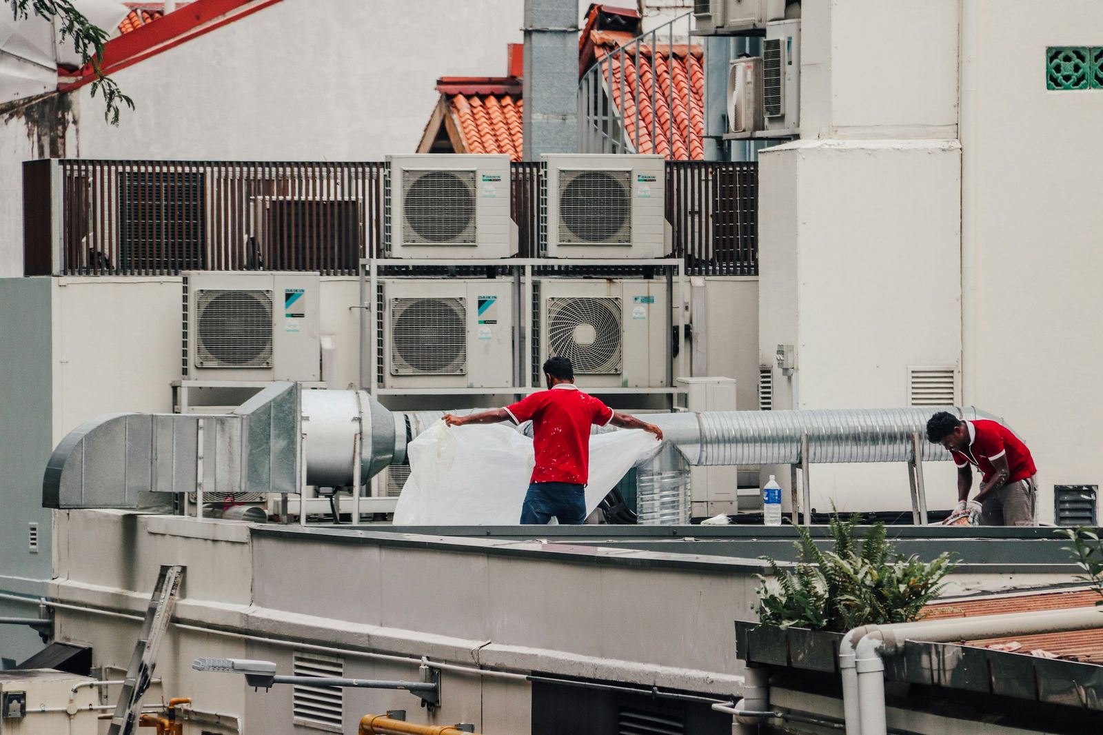 Technicians servicing rooftop condensing units and ductwork
