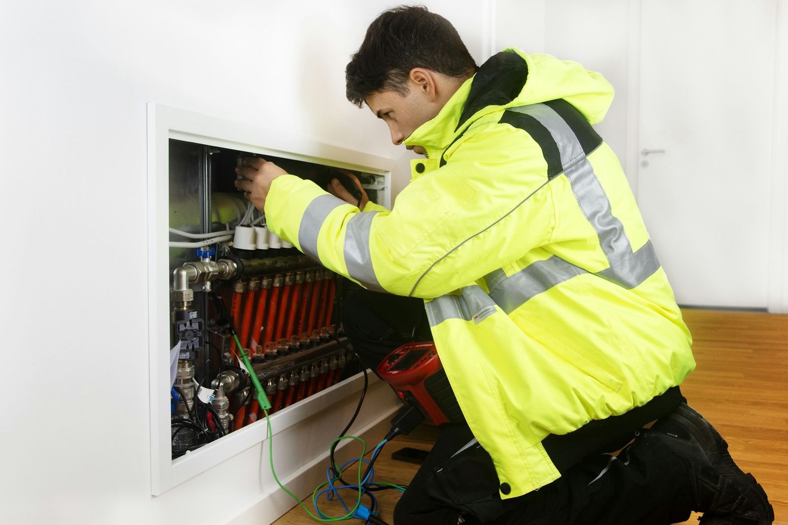 Corbel technician in a high-visibility jacket working on a heating manifold
