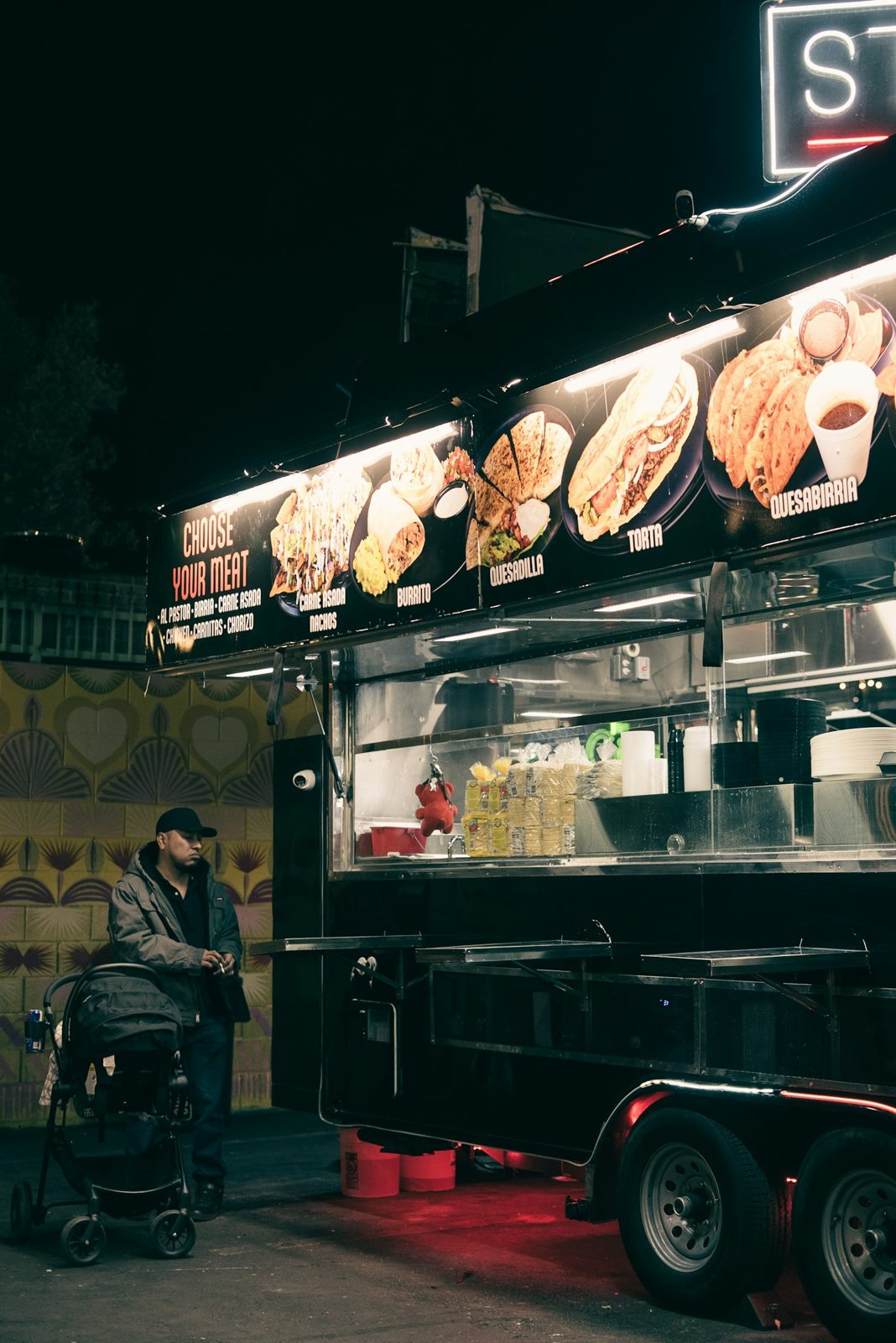 A food truck lit up at night with a guest standing outside