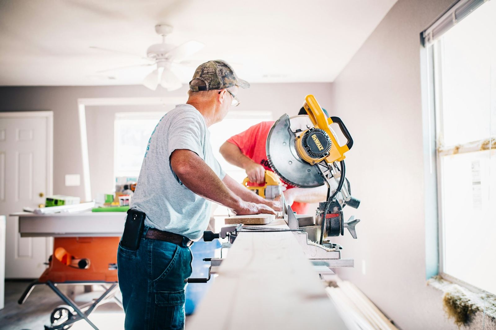 Carpenter cutting trim with a miter saw in a bright room