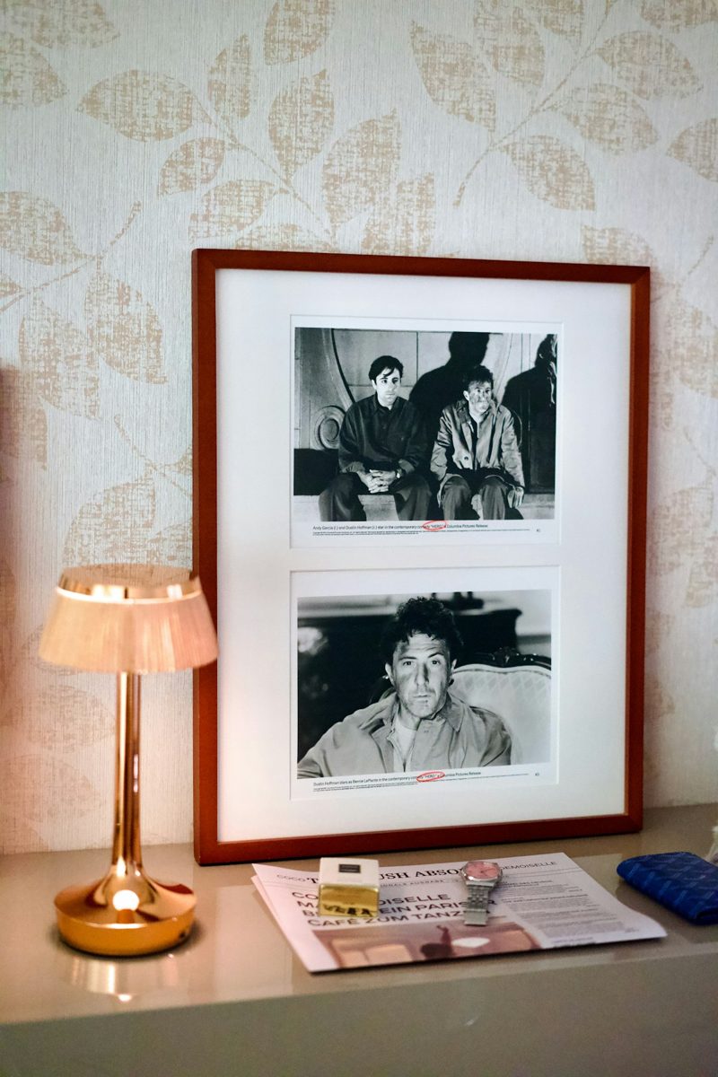 A framed black and white movie still on a table with a lamp and watch