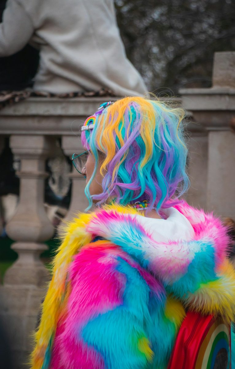 Selective color photography of woman wearing blue, yellow, and pink coat and hair