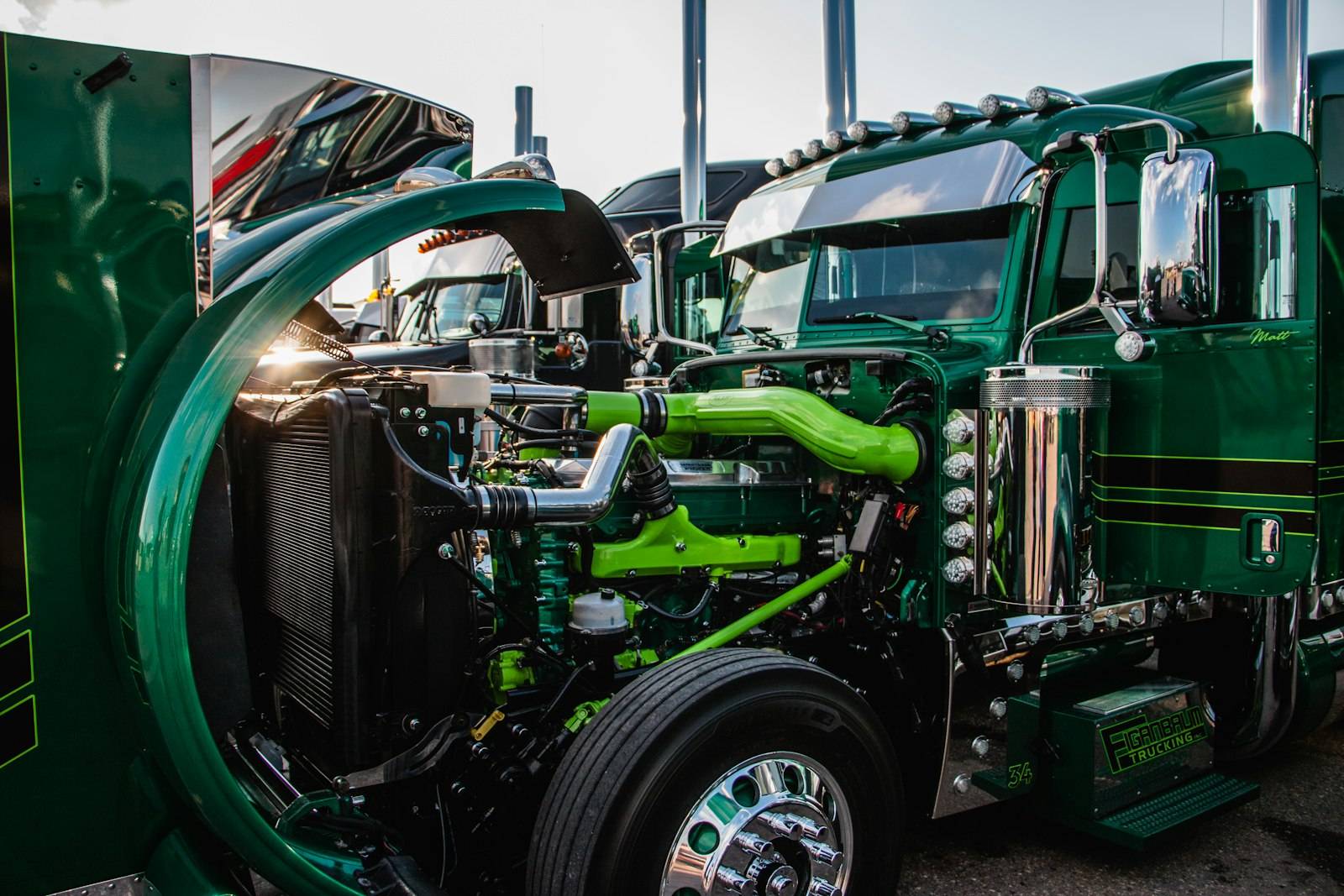 Open hood of a green semi truck showing the engine
