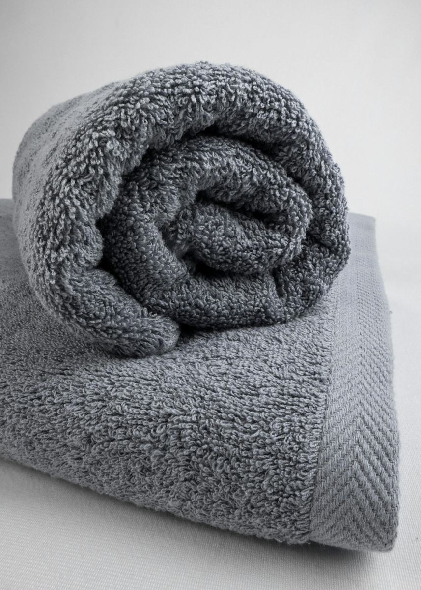 A gray towel folded on top of a bed