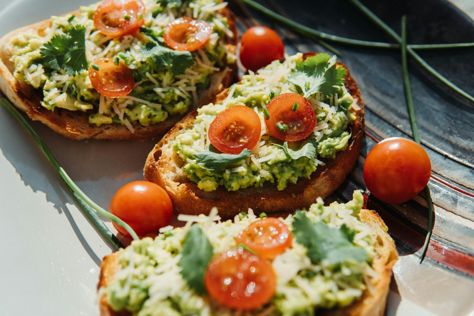 Avocado toasts topped with cherry tomatoes and herbs