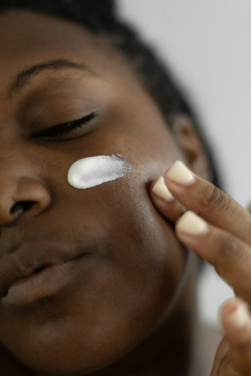 A woman is putting a lotion on her face
