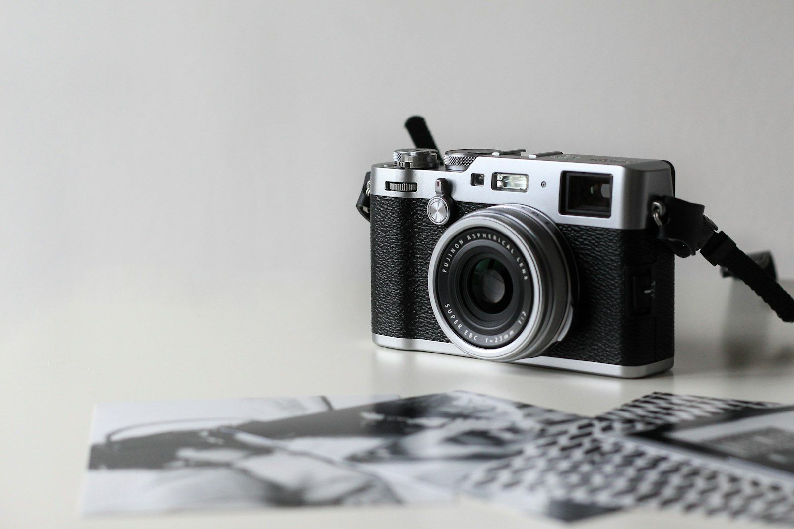 Silver film camera on a table with prints