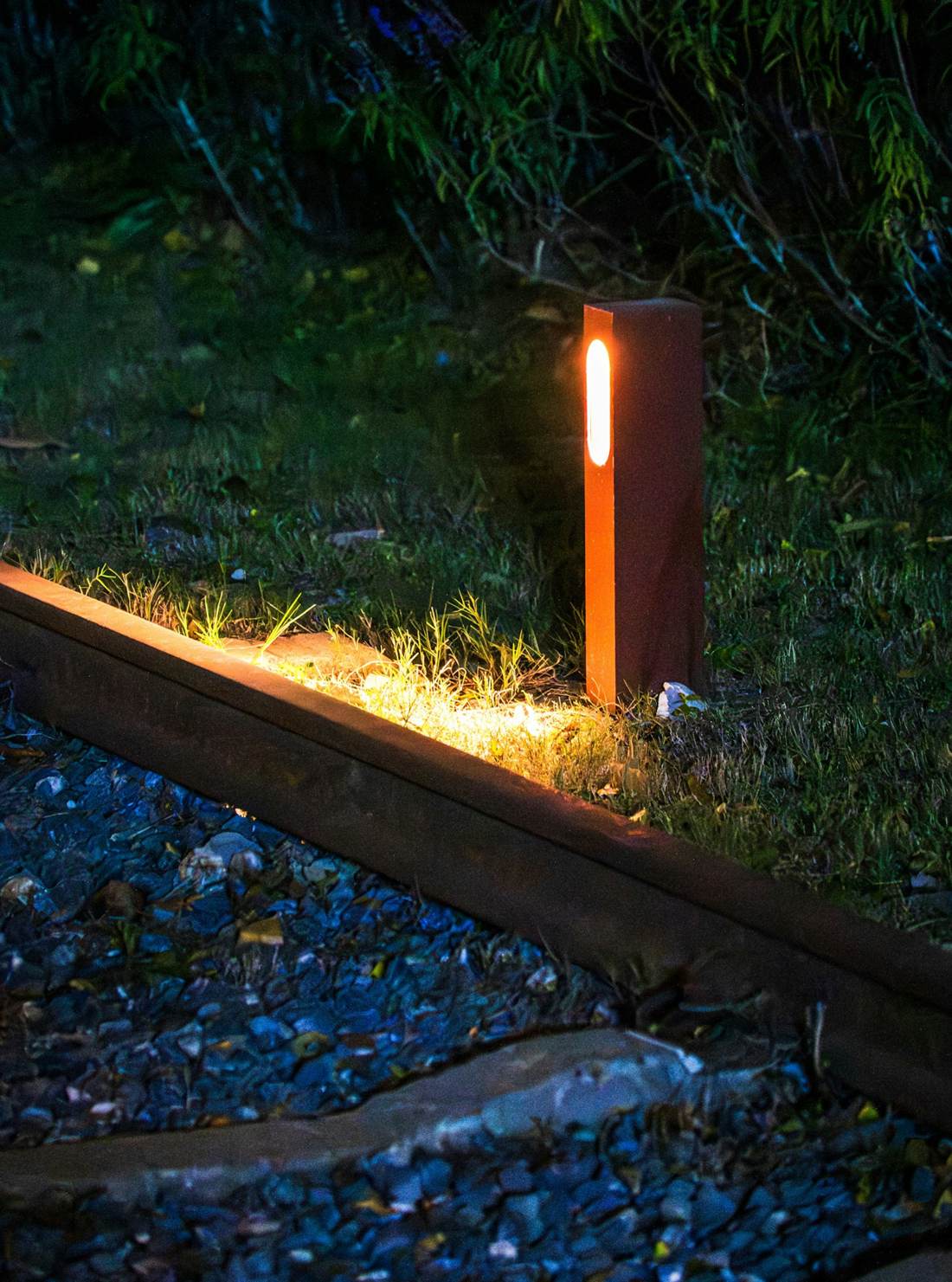 Bollard light glowing beside a garden path