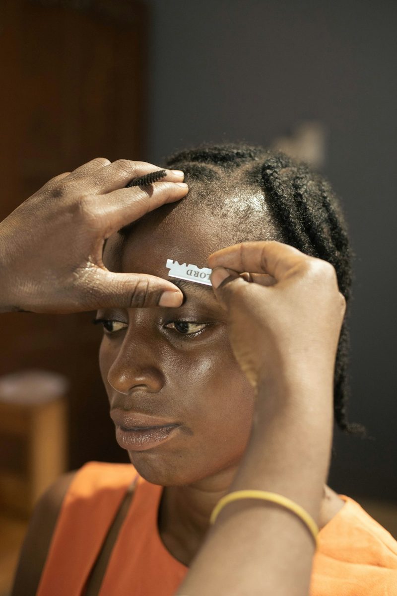 Hands groom a woman's eyebrow with a styling tool
