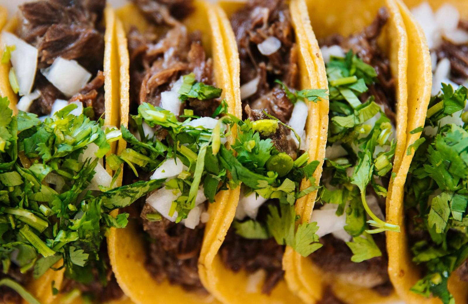 Row of tacos with cilantro and onion