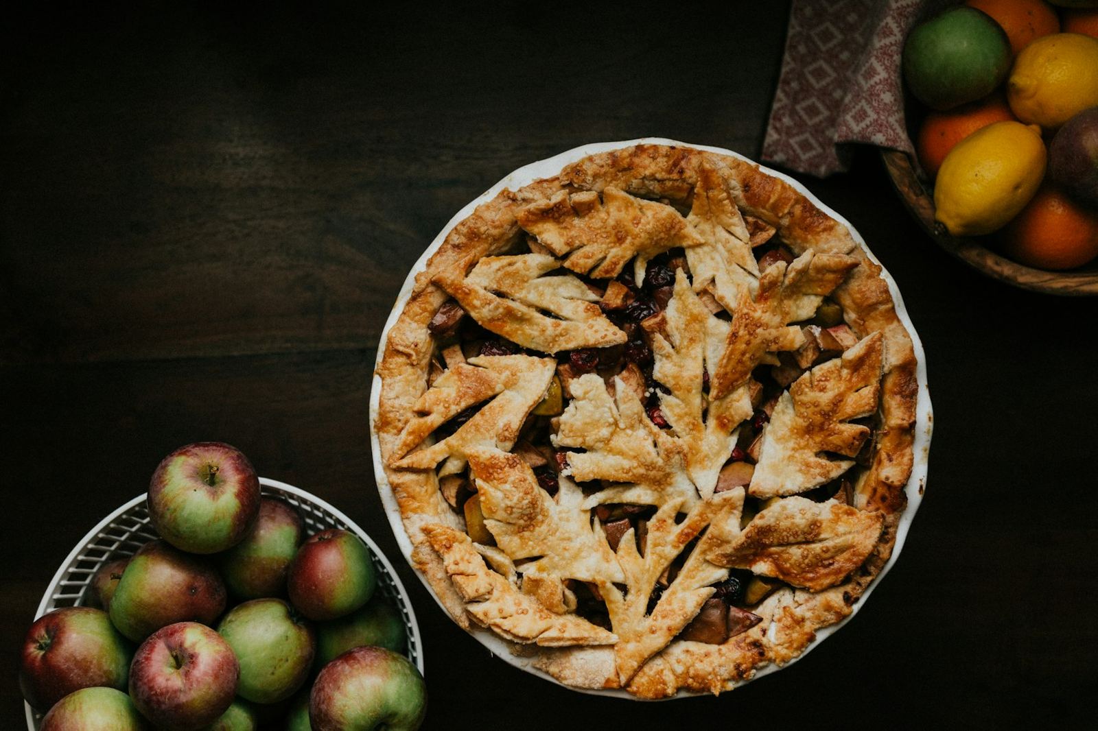 A whole fruit pie with a leaf-cut crust on a dark table
