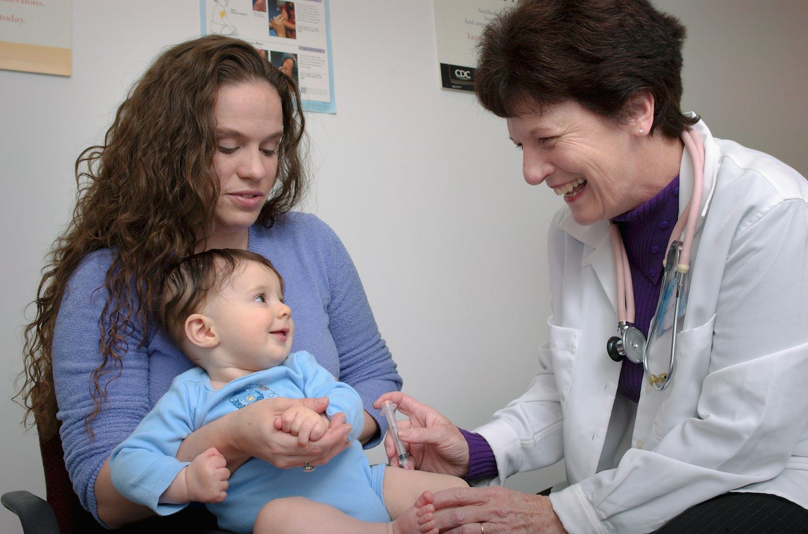 Pediatrician smiling at a baby held by a parent