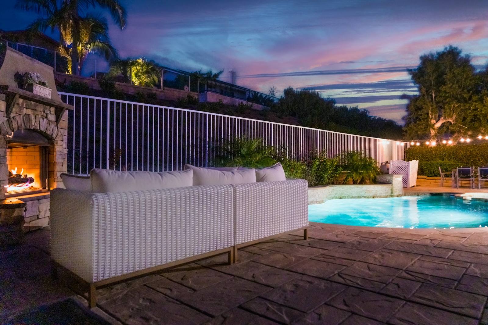 Pool and lounge by a stone fireplace at dusk