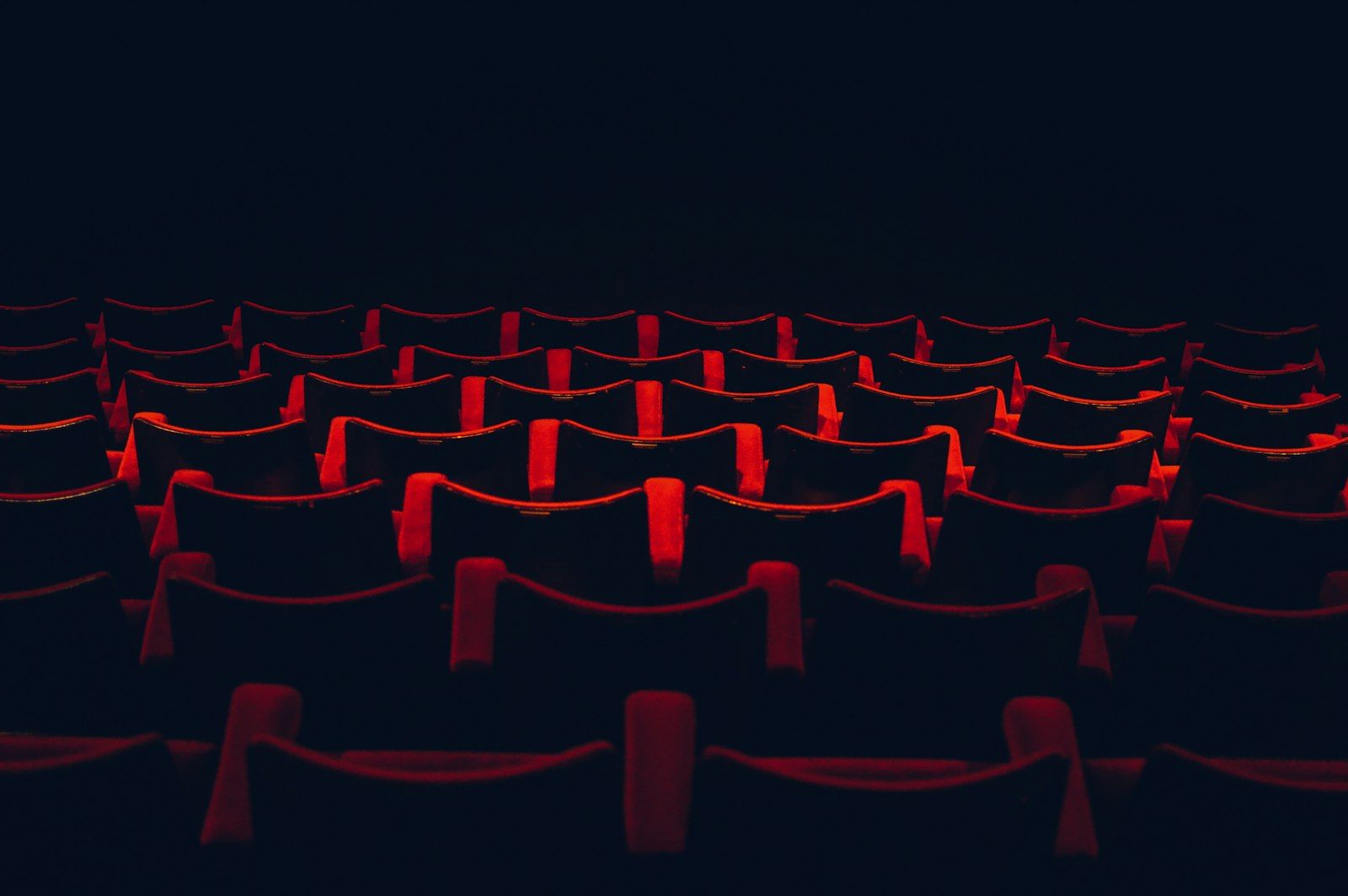 Dark cinema with rows of red seats