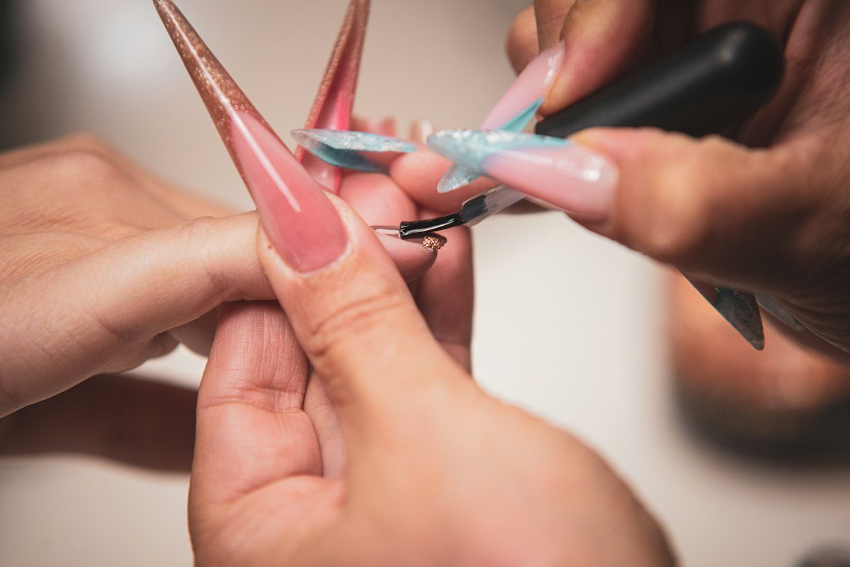 A manicurist paints long artificial nails