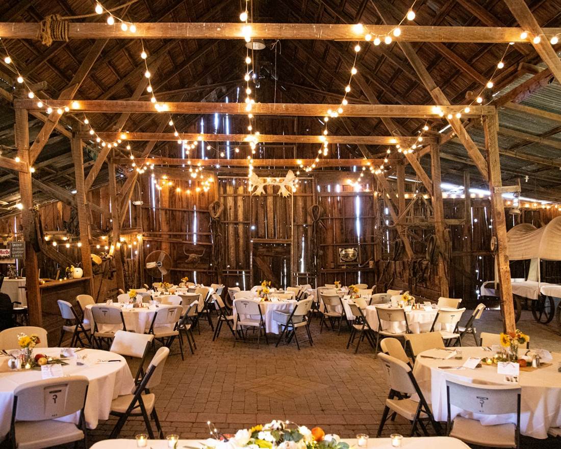 Barn hall set for a wedding dinner with string lights