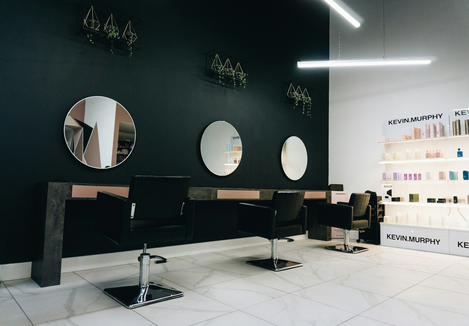 Round mirrors above black styling chairs