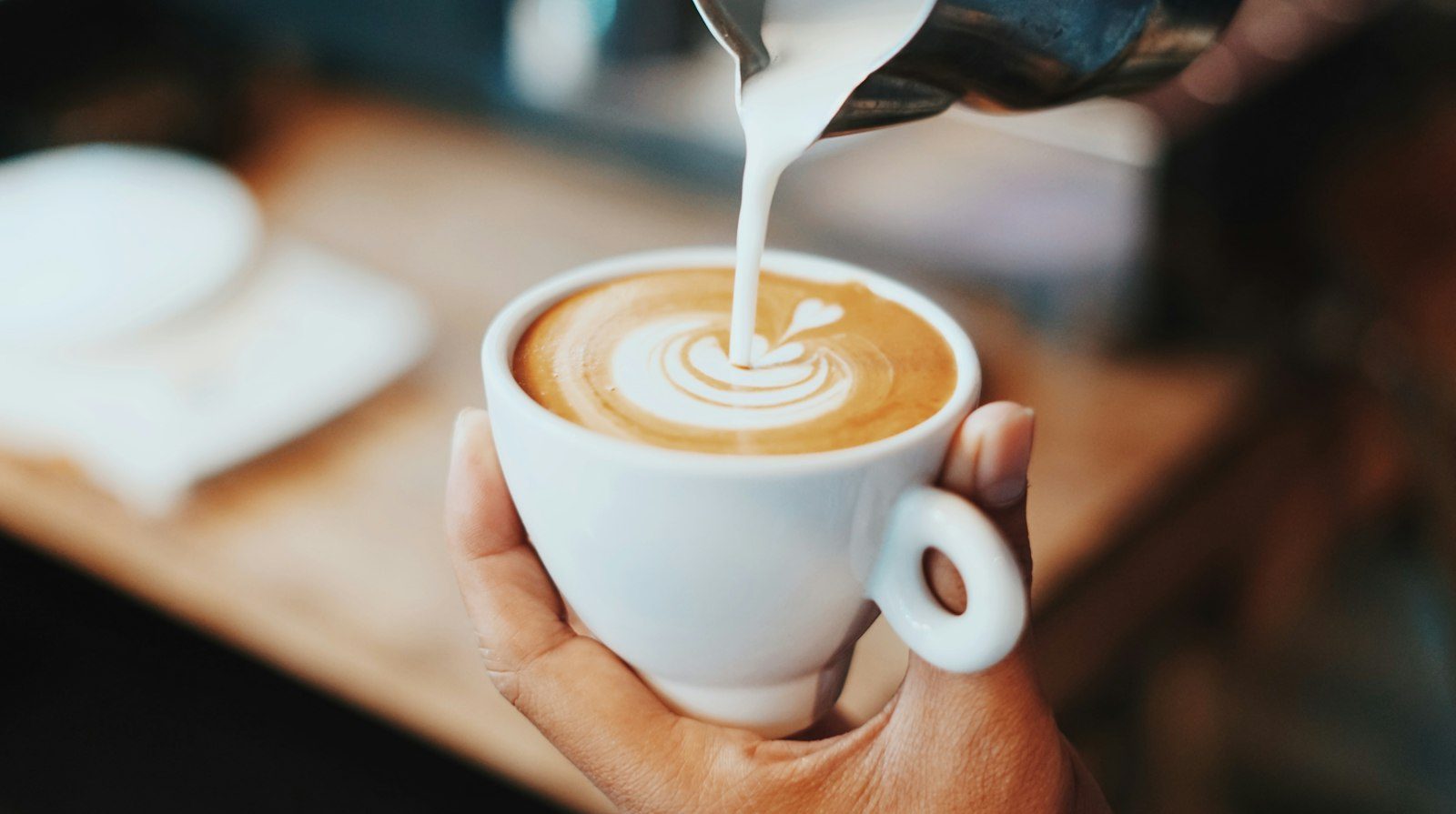 Milk being poured into a latte to make a heart
