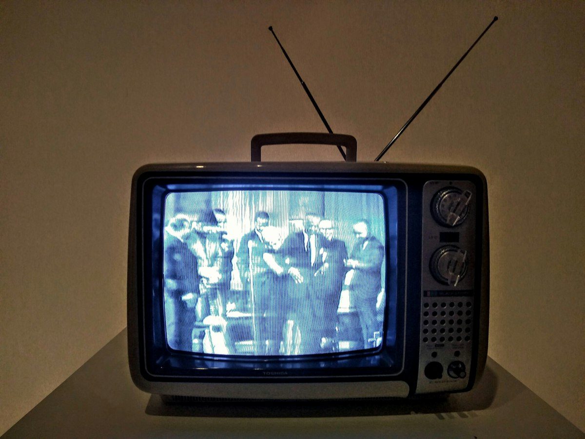 Black crt tv turned on on white table