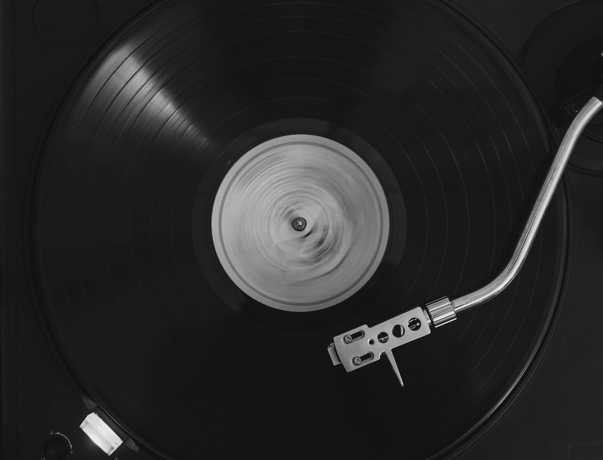 A black vinyl record spinning on a turntable with a silver tonearm